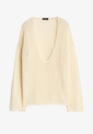 Kremowy, luźny sweter dzianinowy z głębokim dekoltem w kształcie litery V, opadającymi ramionami i postrzępionym dołem, z wyraźnym, otwartym splotem.