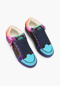 Scarpe da ginnastica colorate con una combinazione di materiali turchese, viola e marrone, con lacci spessi blu navy e suole in gomma testurizzate.