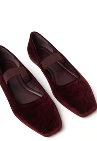 Pair of dark red velvet ballet flats with square toes and elastic straps across the instep on a white background.