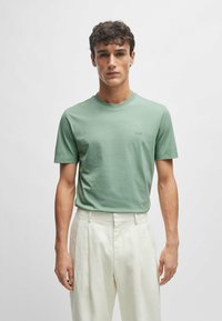 Lichtgroen t-shirt met korte mouwen van zachte stof met een ronde hals. Bevat een klein logo op de borst. Gecombineerd met witte broeken.