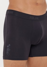 Zwarte katoenen boxershorts met een zachte, elastische tailleband. Voorzien van een aansluitend ontwerp, naadloze zijkanten en een klein gedrukt logo nabij de zoom.