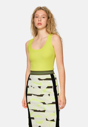 Lime green fitted tank top with a scoop neckline, paired with a patterned pencil skirt featuring black and light green stripes on a white base.