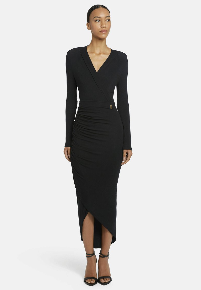 Schwarzes langärmeliges Wickelkleid mit tiefem V-Ausschnitt, Raffung und knöchellangem Saum. Mit einem goldenen Akzent und glatter Stoffstruktur.