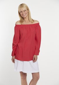 Červená off-shoulder blůza s nařaseným elastickým výstřihem a dlouhými rukávy, doplněná o bílou sukni, hladký materiál, volný střih.