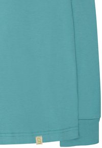Türkise Langarmshirt aus weichem Material, mit einem runden Ausschnitt, genähtem Saum und einem kleinen Stoffetikett unten links.
