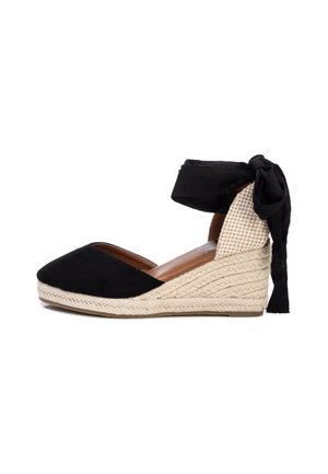 Sort kileespadrille med flettet jutesål, lukket tå og stofbånd, der bindes om anklen med en sløjfe bagpå.