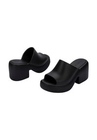 Mules negros con tacón bloque y punta abierta, con material mate liso y diseño de parte superior redondeada. Suela texturizada para mayor agarre.