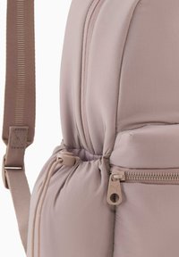 Sac à dos rose gonflé en tissu doux avec une texture lisse ; il comporte un compartiment zippé et des bretelles réglables assorties.