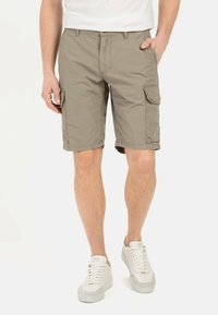 Khaki cargoshorts van lichtgewicht stof, met twee zijzakken, een enkele achterzak en een comfortabele pasvorm. Draagt met witte sneakers.