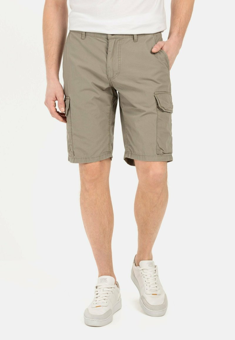 Khaki cargoshorts van lichtgewicht stof, met twee zijzakken, een enkele achterzak en een comfortabele pasvorm. Draagt met witte sneakers.