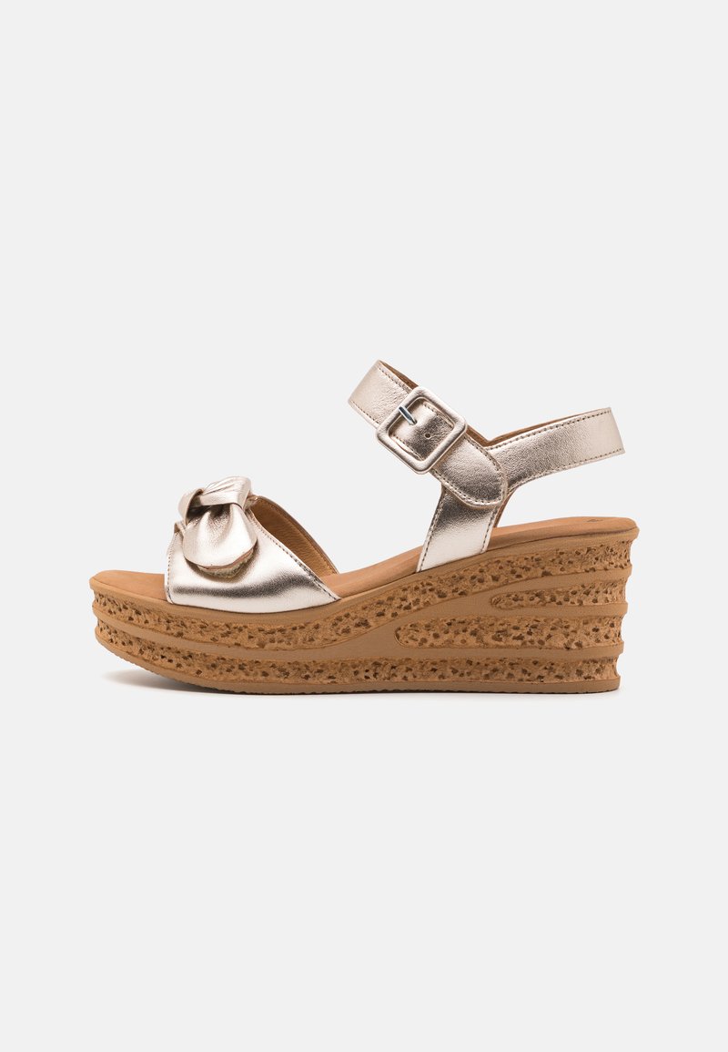 Metallic gold wedge sandals with a knot detail and adjustable ankle strap, featuring a textured tan platform sole.