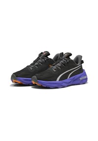 Zapatillas deportivas en negro y gris con parte superior texturizada, acentos plateados, entresuela morada y detalles naranjas en la suela exterior. Adecuadas para correr.