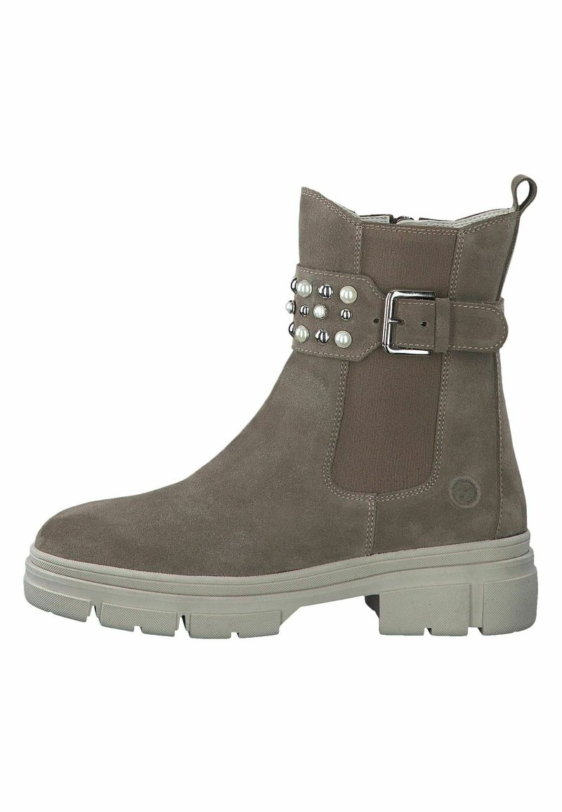 Bottine en daim marron avec côté élastique, bride cloutée et boucle argentée. Semelle épaisse et texturée avec un design chunky pour plus de stabilité.