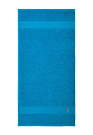 Asciugamano rettangolare blu con bordi texture nella parte superiore e inferiore, con un piccolo logo ricamato di un giocatore di polo arancione nell'angolo in basso a destra.