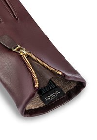 Burgunderfarbene Lederhandschuhe mit goldfarbenem Reißverschluss und einem weichen Innenfutter. Mit einem Markenetikett im Inneren, das hochwertige Materialien präsentiert.