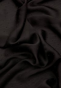 Czarna tkanina o teksturowanej powierzchni, z małymi czarnymi kropkami równomiernie rozmieszczonymi, tworząc subtelny, wyrafinowany wzór.