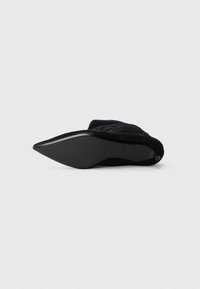 Stivaletto in suede nero con punta affusolata e silhouette eleganti. Presenta una suola liscia e una texture morbida, progettato per un look aderente.