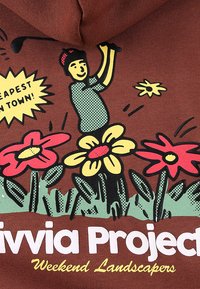 Smeđa hoodica s raznobojnim grafičkim printom cvijeća i lika koji drži vrtni alat, s tekstom "Livvia Project Weekend Landscapers."