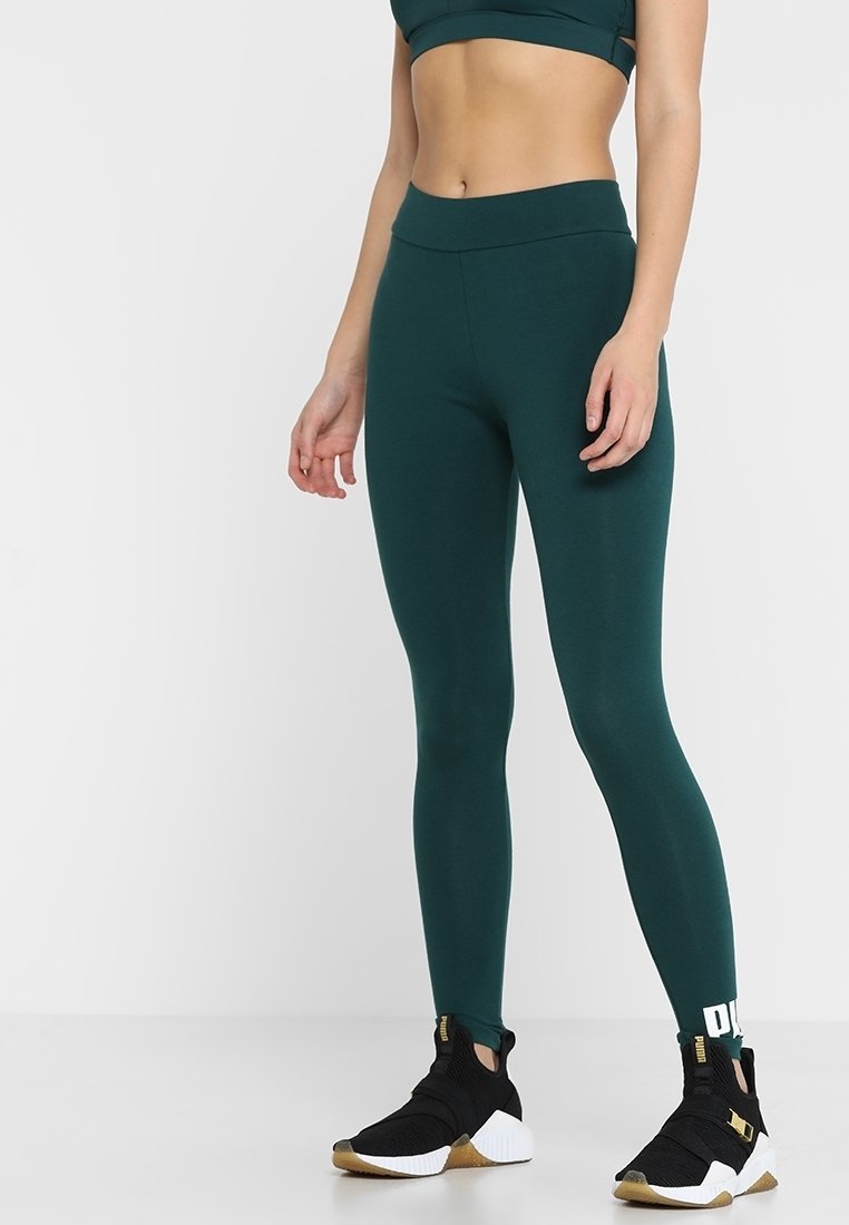 Turkusowe legginsy z wysokim pasem, wykonane z elastycznego materiału. W połączeniu z czarnymi sneakersami z złotą podeszwą i białym logo.