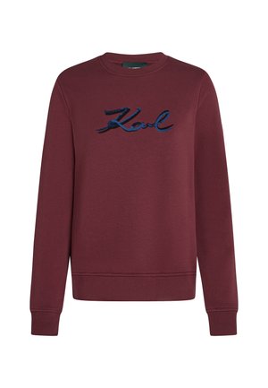 Bordeaux dlouhý rukáv crewneck svetr s modrými flitry na nápisu "Karl" umístěným uprostřed hrudi.