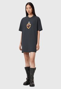 Czarna, oversize sukienka t-shirt z haftowanym wzorem serca z płomieniami. W zestawie z czarnymi, do kolan fasonem botkami z klamrami.