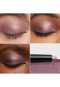 Metalliskt lila ögonskugga applicerad på slutna ögon, som visar en skimrande finish. En svart applikator med rundad spets vilar på texturerat tyg.