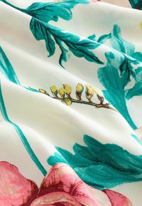Gėlių audinys su žaliais lapais ir rožinėmis gėlėmis ant baltos fono, pasižymintis lygiu paviršiumi ir gyvybingais, tapybiniais raštais.