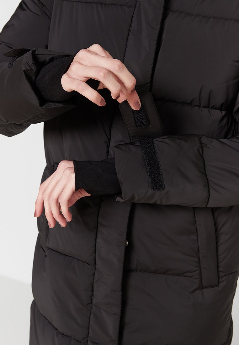 Schwarze Daunenjacke mit einem gesteppten Design, ausgestattet mit einem gesicherten Klettverschluss am Ärmel und einer eleganten, glatten Textur.