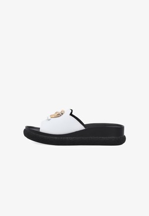 White slide sandal with thick textured black sole and gold chain detail on upper strap, shown in side view on white background.