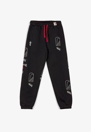 Schwarze Baumwoll-Sweatpants mit rotem Kordelzug, die verschiedene weiße Grafiken und Muster aufweisen, darunter Treppen und Logos an den Beinen.