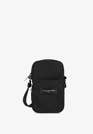 Sac bandoulière en nylon noir avec fermeture éclair, présentant un patch logo à l'avant et une sangle ajustable. Texture lisse, design compact.
