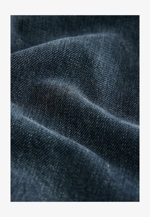 Tessuto in denim blu scuro con una superficie testurizzata, che mostra una trama evidente e leggere variazioni di tonalità. Morbido, di peso medio, con motivi sottili.