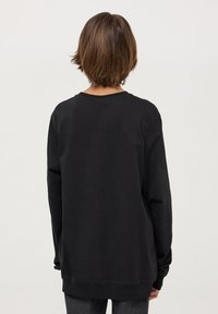 Czarna bluza z długim rękawem, okrągłym dekoltem, luźnym krojem i ściągaczami na rękawach. Gładka tekstura i jednolity wzór, bez widocznych motywów czy akcentów.