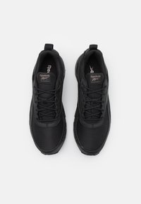 Sorte atletiske sko med en tekstureret mesh-overdel, snørebåndslukning og en polstret sål. Har Reebok-branding på tungen.