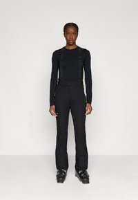 Pantaloni de schi negri cu bretele adjustabile, design ajustat și buzunare cu fermoar. Purtați cu un top negru cu mânecă lungă și cizme de schi.