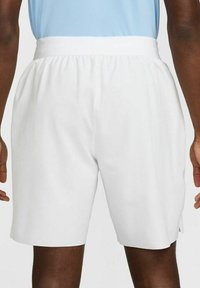 Pantaloni corti bianchi con elastico in vita, design lungo fino al ginocchio, texture liscia e spacchi laterali per una maggiore libertà di movimento.
