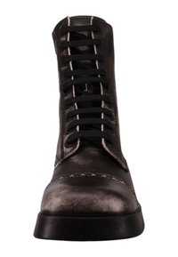Bottines en cuir noir à bout arrondi, avec des accents de couture blanche et des lacets noirs. La surface est lisse et légèrement brillante.
