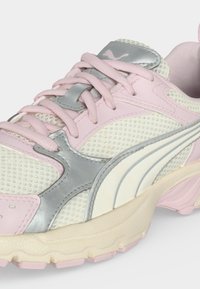 Ροζ και λευκό αθλητικό παπούτσι Puma με αναπνεύσιμη επάνω επιφάνεια από πλέγμα, ασημί λεπτομέρειες, ροζ κορδόνια και υφασμένο μπεζ πάτο, εμφανίζεται σε γωνία.