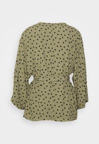 Blusa verde oliva con pois neri, vestibilità rilassata, maniche lunghe e una cinta in tessuto in vita, con bottoni.