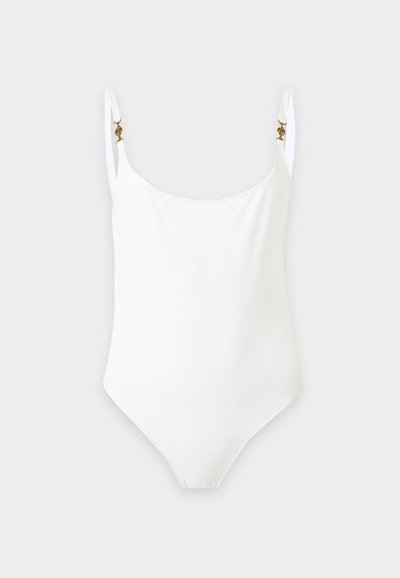 Maillot de bain une pièce blanc avec fines bretelles réglables et petites attaches décoratives dorées sur un fond clair.