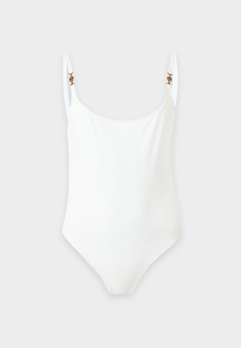 Maillot de bain une pièce blanc avec fines bretelles réglables et petites attaches décoratives dorées sur un fond clair.
