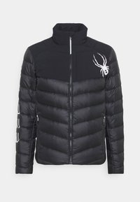 Schwarze Pufferjacke mit hohem Kragen, Reißverschluss und einem Spinnenlogo auf der Brust; verfügt über gestickte Abschnitte und Seitentaschen.
