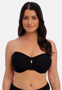 Haut bandeau noir avec tissu froncé, design sans coutures et accent doré au centre, offrant une texture lisse.