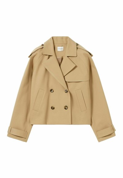 Manteau trench court beige avec un design à double boutonnage, grandes poches avant et épaules structurées. Doté de boutons dorés et de lanières aux poignets.