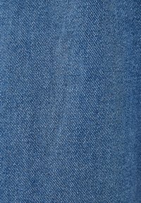 Ljusblå denimtyg med en texturerad yta, som har diagonala vävningar och subtila variationer i färgintensitet.