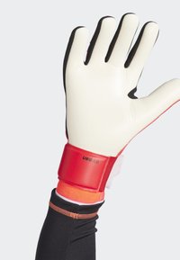 Doelmanhandschoen met een witte latex palm, zwarte stoffen accenten en een rode band met het label "URG 3.0." Heeft een nauwsluitend ontwerp.