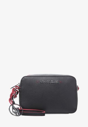 Sac bandoulière rectangulaire noir Armani Jeans avec détail rouge, finition texturée et pendentif logo métallique circulaire attaché à la sangle.