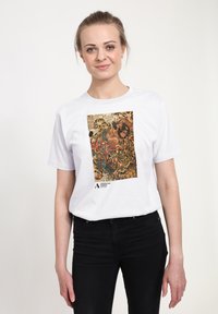 Bílé bavlněné tričko s barevným, detailním motivem válečníka a tygrů, s textem a logem v levém dolním rohu.