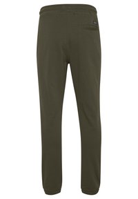 Olivgrüne, weiche Baumwoll-Jogginghosen mit elastischem Bund, schmal zulaufenden Beinen und einer einzigen Gesäßtasche. Glatte Textur und minimale Nähte.