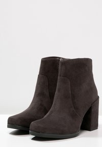 Mørkegrå faux suede ankelstøvler med blokhæle, der har en glat tekstur, rund tå og lynlåsdetalje i siden.